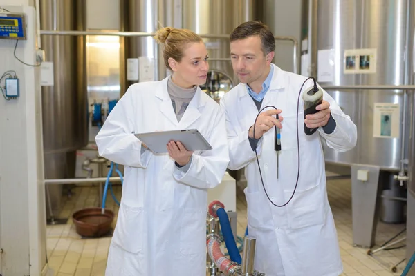 People next to vats holding tablet and probe — Stock Photo, Image