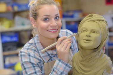 artisan woman finishing sculpture in a studio clipart