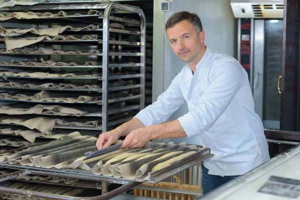 Stolta bagare baka baguette bröd i hans kök — Stockfoto
