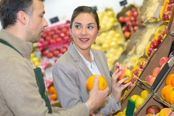 Lachende vrouw kiezen van verschillende vruchten in farm food winkel display — Stockfoto