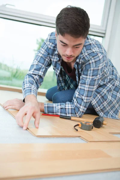 Handsome man fitting a wooden plank — Stock Photo, Image