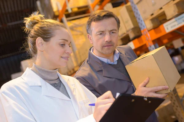 De vrouwelijke werknemer magazijn in uniform controleren cardboxes — Stockfoto