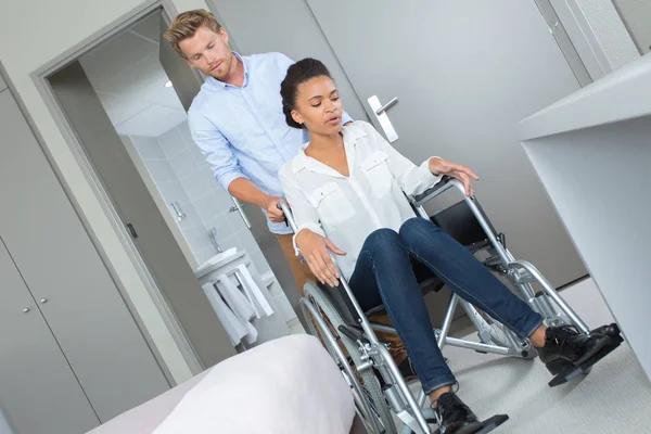 Amoroso chico con su novia en silla de ruedas en la habitación —  Fotos de Stock