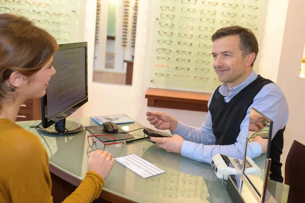 Optiker och kunden satt vid skrivbord — Stockfoto