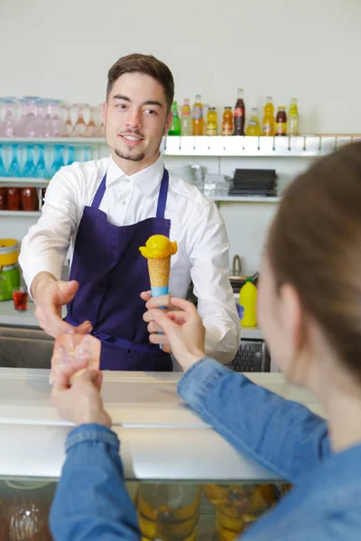 Dívka zaplatí mangoice krém číšník v obchodě — Stock fotografie