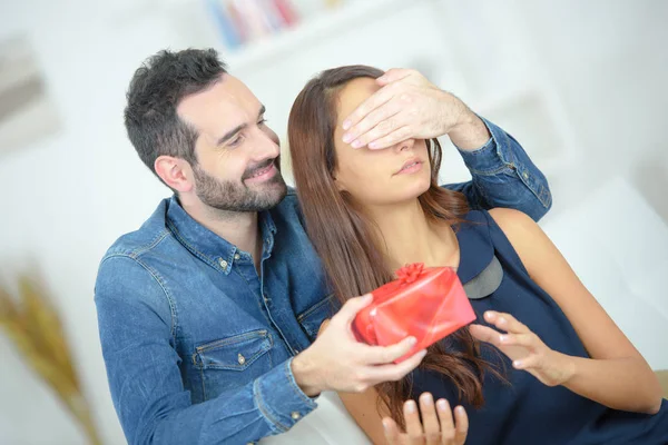Young attentive man offering gift to his beloved girlfriend — Stock Photo, Image