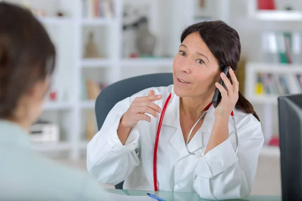 Médico com paciente e falando ao telefone — Fotografia de Stock