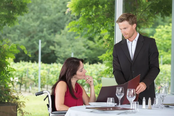 Junge schöne Frau im Rollstuhl bestellt in einem Restaurant — Stockfoto