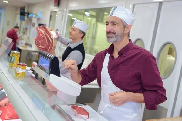 Açougueiro supermercado auxiliando um cliente — Fotografia de Stock