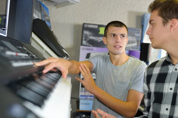 Счастливый молодой человек пробует пианино в музыкальном магазине — стоковое фото