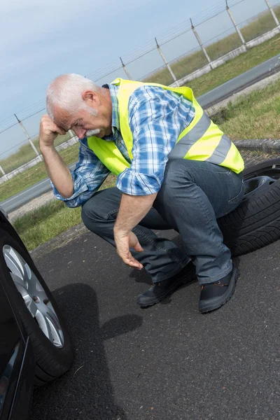 Mutloser Rentner kann Autoreifen nicht wechseln — Stockfoto