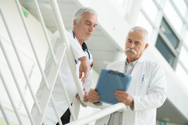 Mitten delen av läkare diskutera över Urklipp på sjukhus — Stockfoto