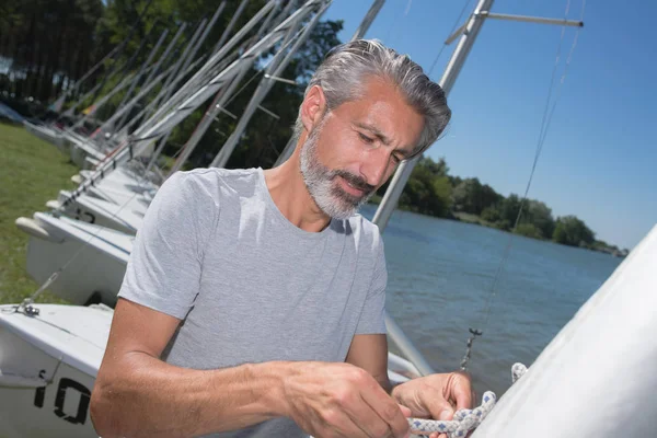 Attractive middle-aged man preparing sport sailboat — Stock Photo, Image