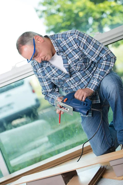 Man voorbereiding te snijden laminaatvloeren met decoupeerzaag — Stockfoto