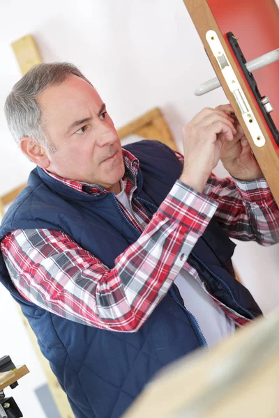 Mature male locksmith fixing door handle at a home — Stock Photo, Image