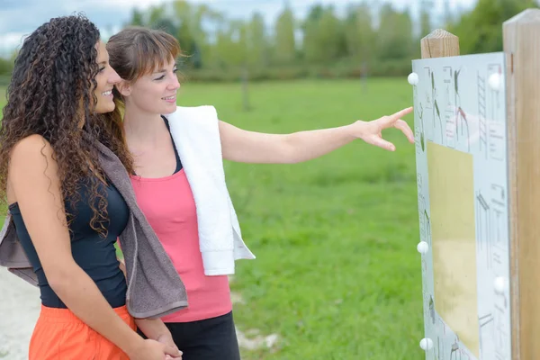 Mujeres señalando el aviso del equipo del parque — Foto de Stock