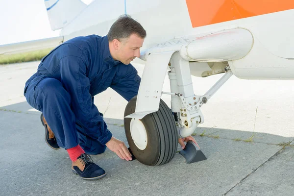 Worker checking undercarriage of plane — Stock Photo, Image