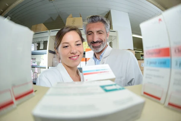 Farmacêuticos verificando medicamentos na prateleira na farmácia — Fotografia de Stock