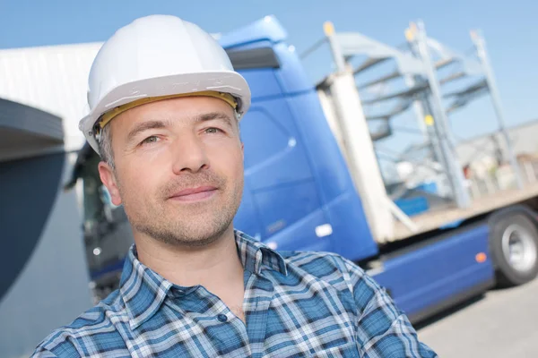 Porträtt av man i hardhat framför lastbil — Stockfoto