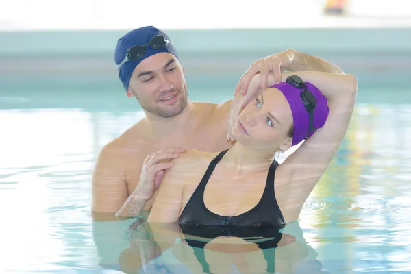 Mujer estirándose con el entrenador dentro de una piscina — Foto de Stock