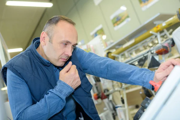 Mecánico repara una máquina en una tienda — Foto de Stock