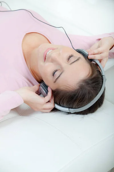 Lady lying on back listening to headphones — Stock Photo, Image