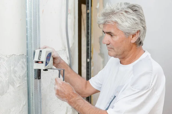 Bauherr überprüft Wand mit Gerät — Stockfoto