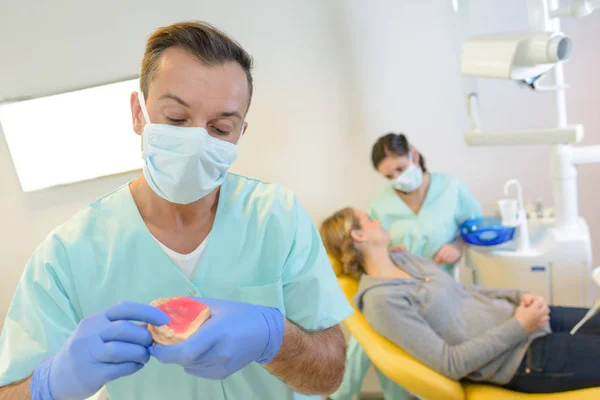 Dentista curando uma paciente mulher no consultório odontológico — Fotografia de Stock