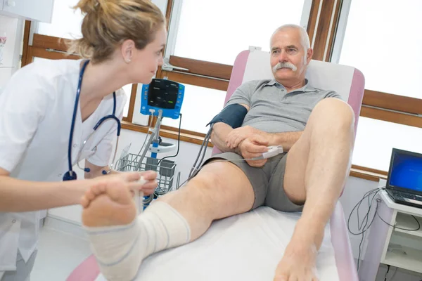 Medico fasciatura gamba di paziente in ospedale — Foto Stock