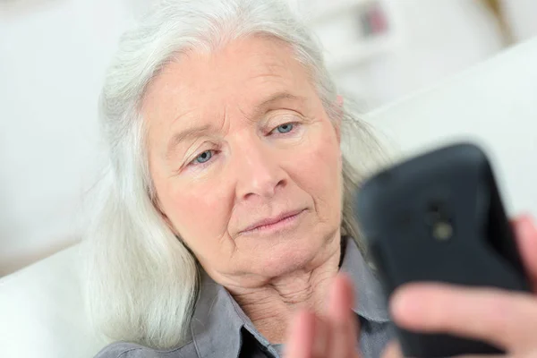 Bejaarde vrouw verzendt sms op mobiele telefoon — Stockfoto