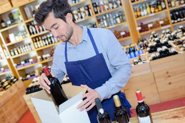 Vendedor usar delantal preparación caja con botellas en la tienda de vinos — Foto de Stock