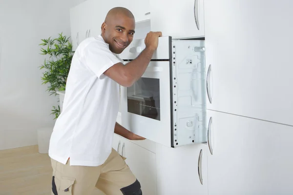 Worker installing an oven in a kitchen — Stock Photo, Image