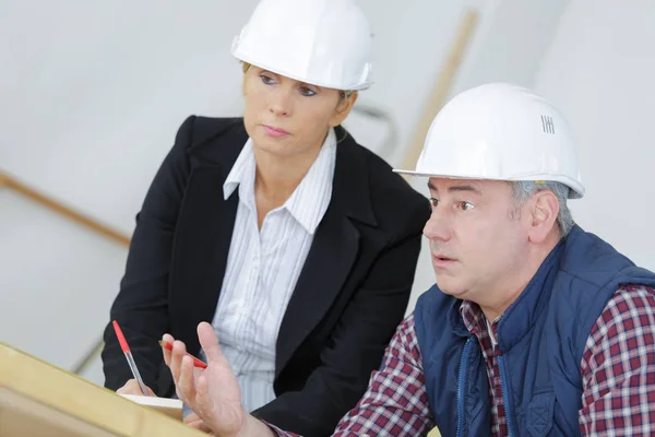 A female architect and a foreman examining blueprints — Stock Photo, Image