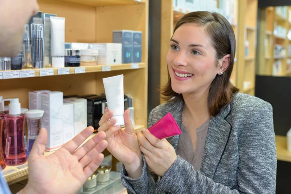 Πωλήτρια δείχνει δύο προϊόντα ομορφιάς σε πελάτη — Φωτογραφία Αρχείου