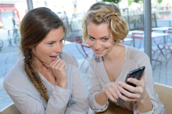 Друзі дивляться на смартфон у кафе — стокове фото