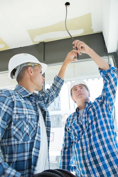 Twee elektriciens gloeilamp voor energiebesparende lamp wijzigen — Stockfoto