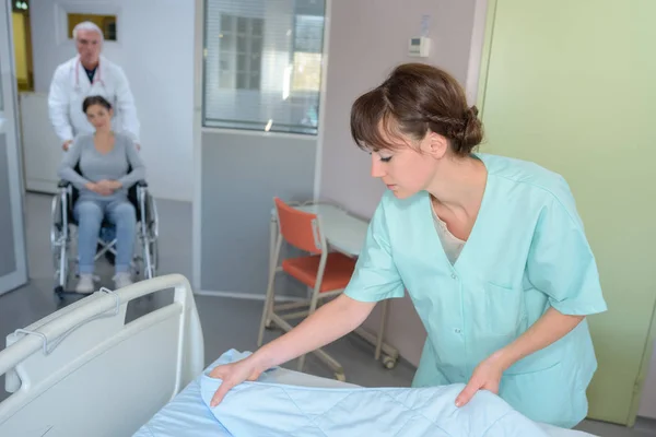 Krankenschwester bereitet Laken auf Krankenhausbett vor — Stockfoto