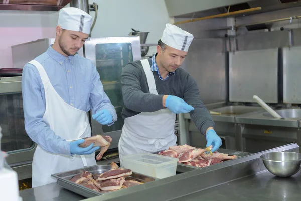 Apprenti et chef préparant la viande dans la cuisine du restaurant — Photo