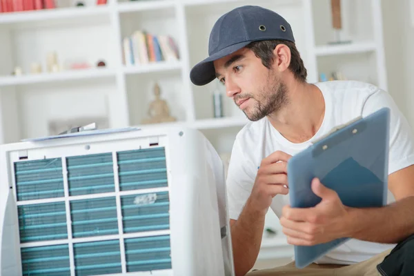 Handsome technician checking the ac at clients home — Stock Photo, Image