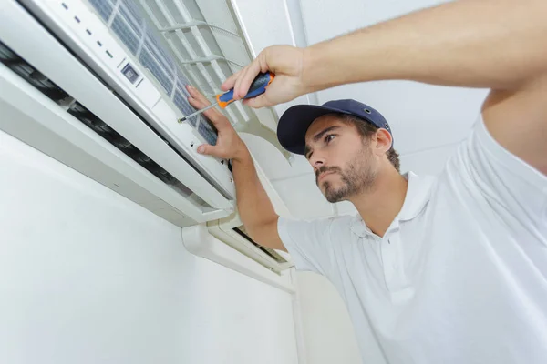 Portret van halverwege volwassen mannelijke technicus reparatie Air Conditioner — Stockfoto