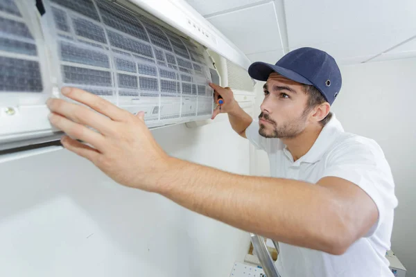 Portret van halverwege volwassen mannelijke technicus reparatie Air Conditioner — Stockfoto