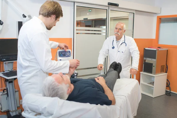 Patiënt op bed en artsen controleren op hem te leggen — Stockfoto