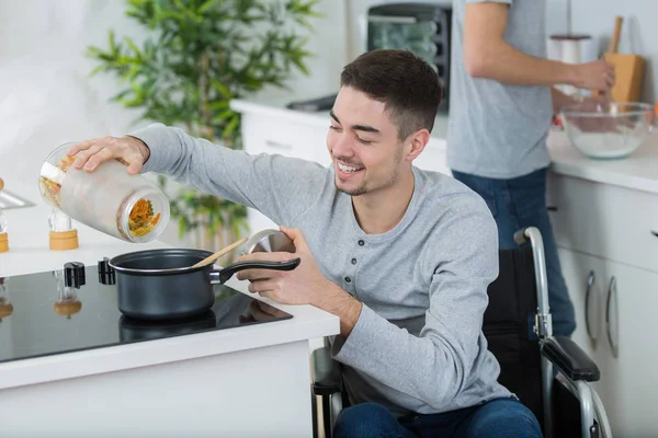 Инвалид молодой человек в инвалидной коляске на кухне — стоковое фото