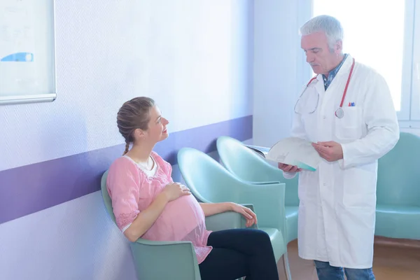 Médico dando notícias a uma mulher na sala de espera do hospital — Fotografia de Stock