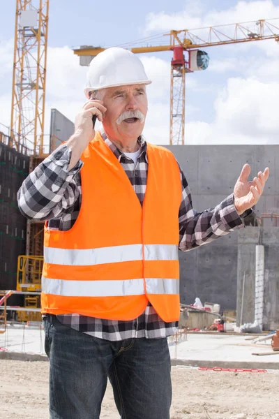 Ingeniero constructor en el sitio de construcción hablando por teléfono — Foto de Stock