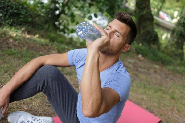 Homem beber água enquanto descansa durante o treino de treino ao ar livre — Fotografia de Stock