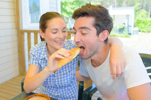 Woman feeding a croissant to her partner — Stock Photo, Image