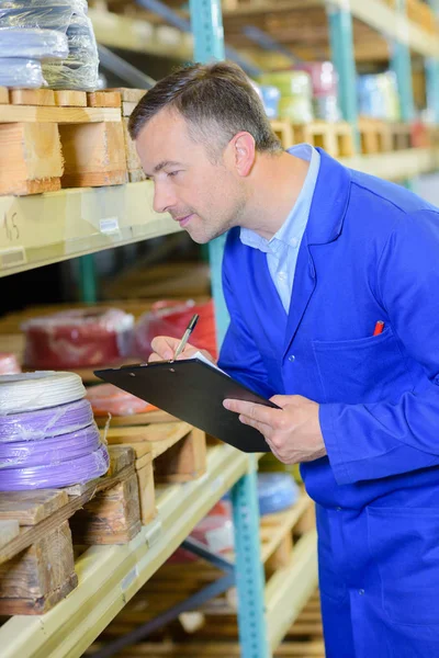 Mann in Geschäften schreibt auf Klemmbrett — Stockfoto