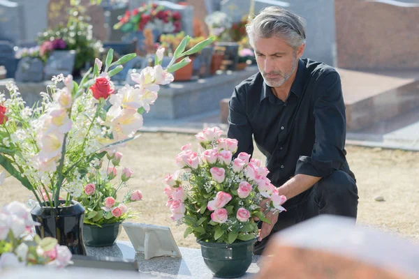 Man brengen van bloemen op graf — Stockfoto