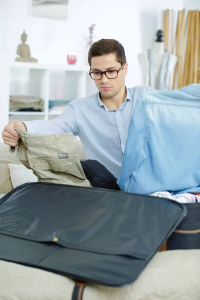 Geschäftsmann packt Kleidung in Reisetasche — Stockfoto